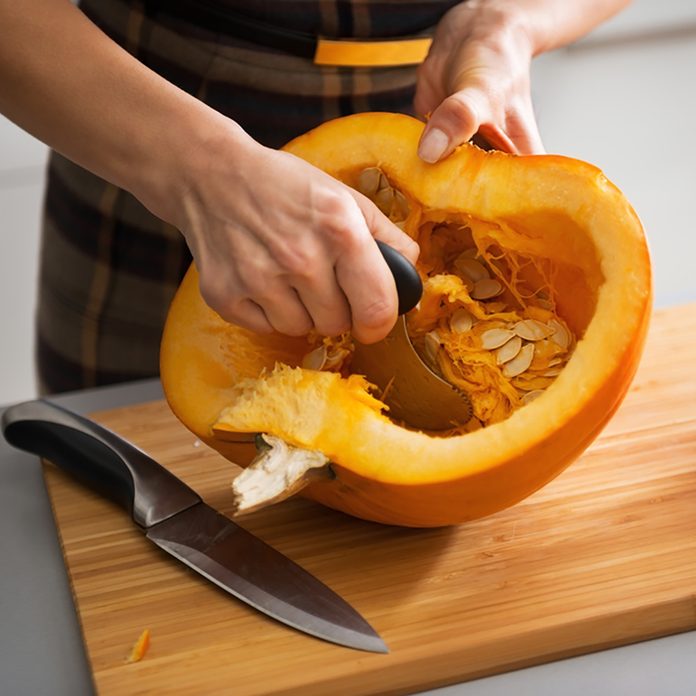 Closeup on young housewife removing filling from pumpkin