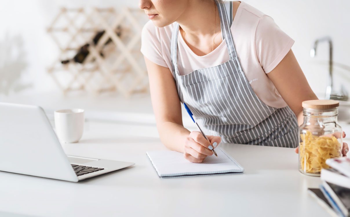 Dedicated hostess making notes in her cookbook
