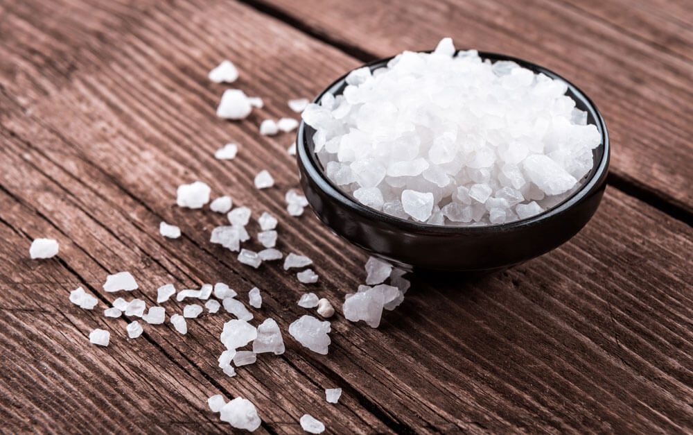 Sea salt in bowl on wooden background