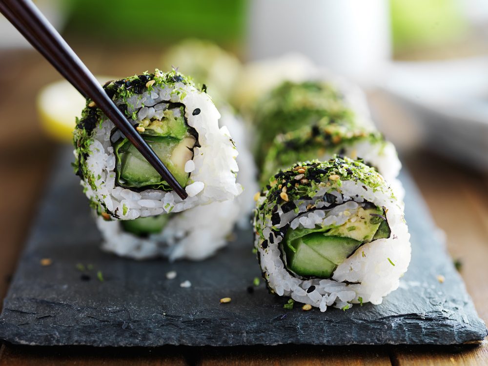 Healthy kale and avocado sushi roll with chopsticks