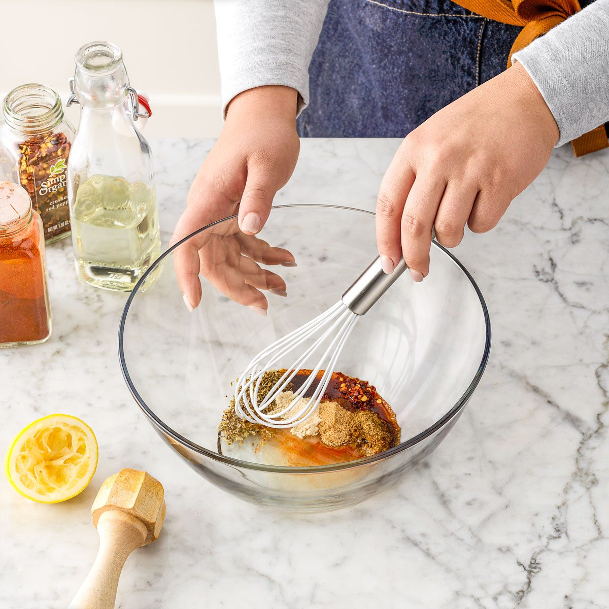 Mixing Spices, Oil and Lemon in a Large Glass Bowl on Marble Surface