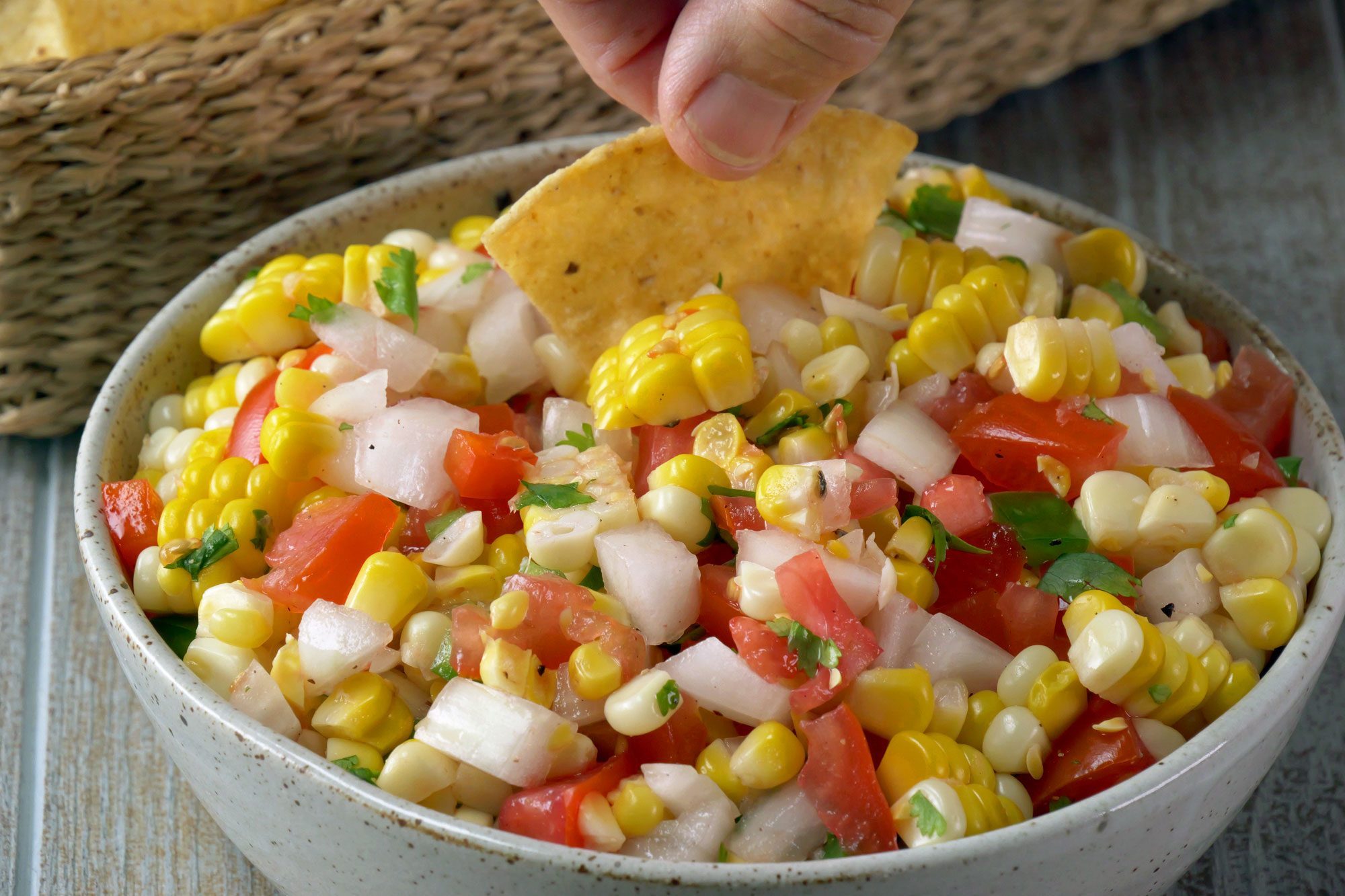 Corn Salsa in a large bowl dipping nacho into Corn Salsa