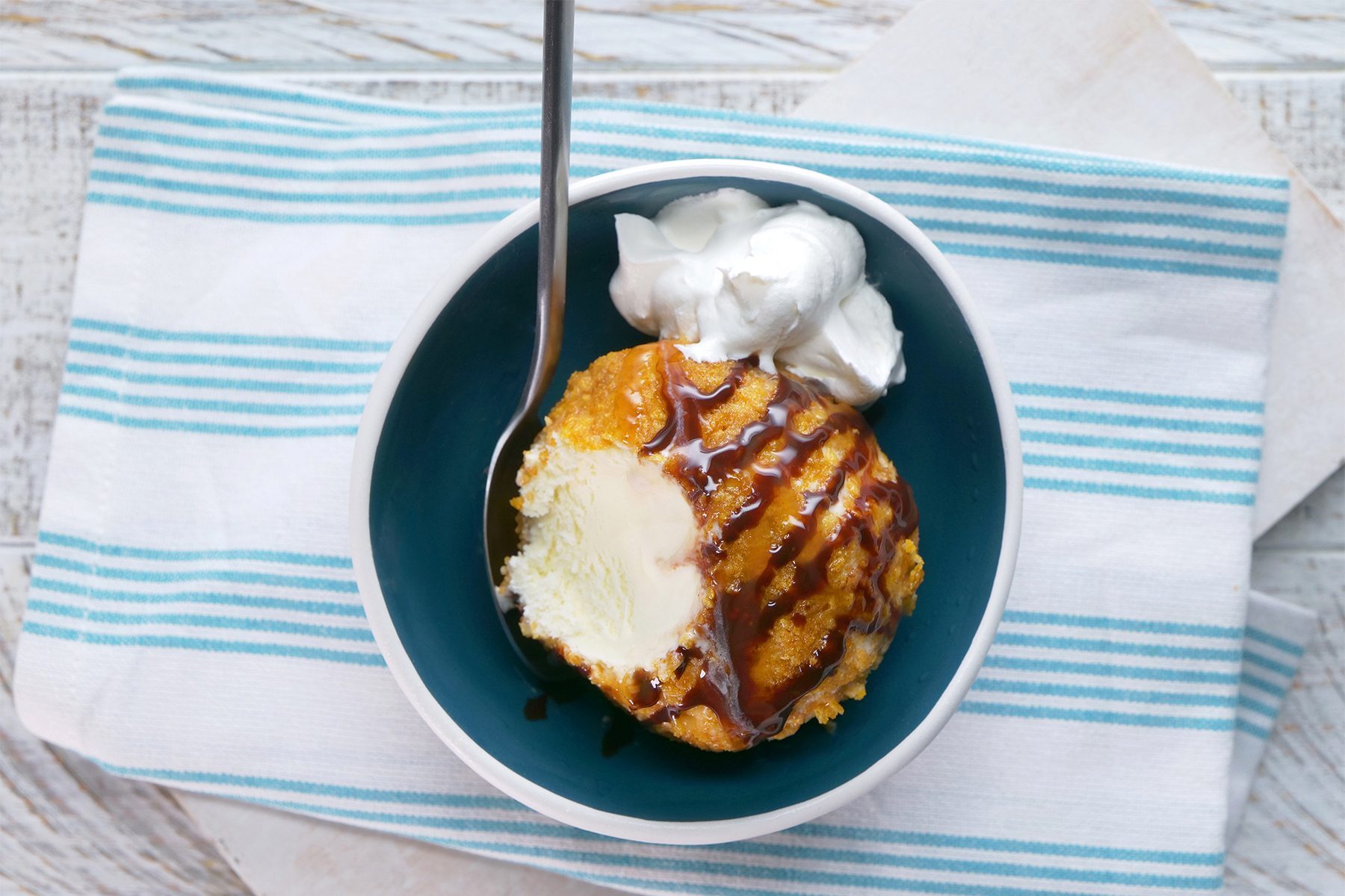 overhead shot; white wooden background; Fried Ice Cream served in a small bowl over kitchen towel