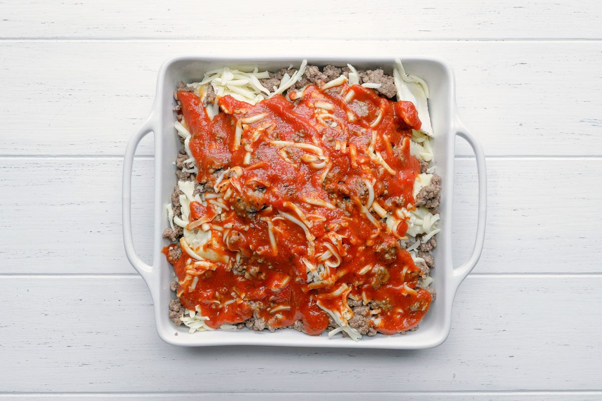 the top layer of the lasagna topped with sauce and cheese