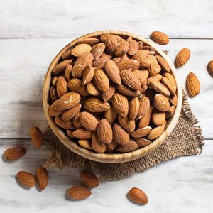 Almonds in brown bowl on wooden background