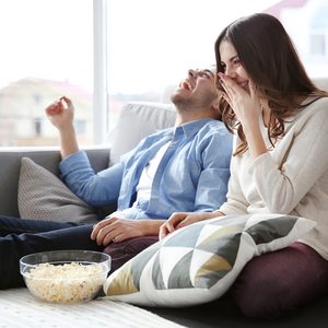 Young couple watching TV on a sofa at home