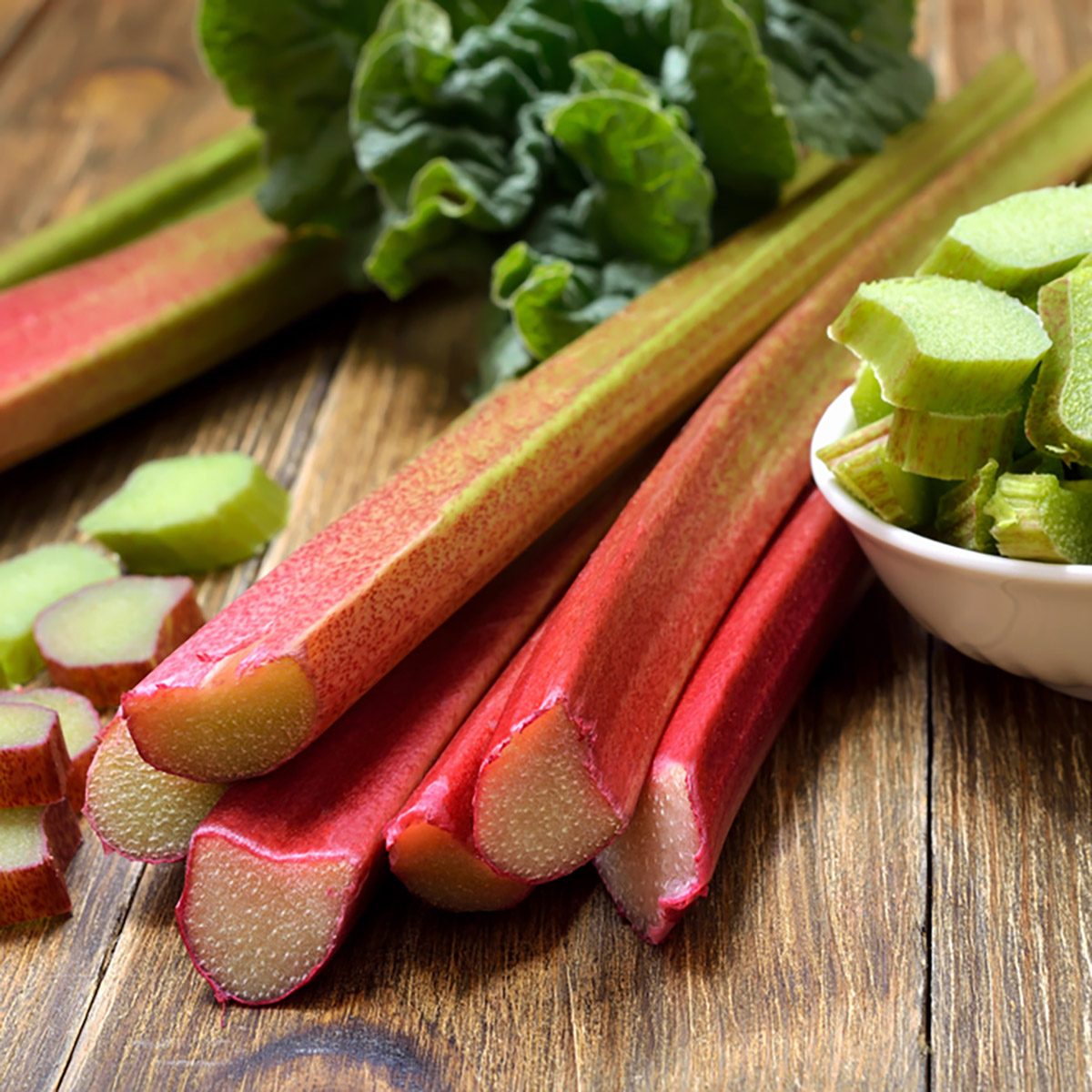 Rhubarb on wooden table. Fresh rhubarb on white bowl