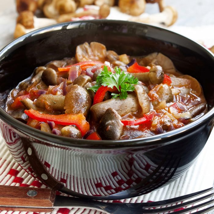 fresh mushroom stew with vegetables and raw mushrooms on the background