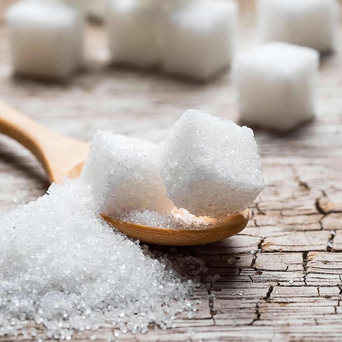 white sugar in wood spoon on wood table