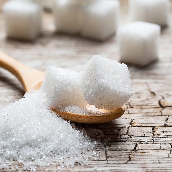 white sugar in wood spoon on wood table