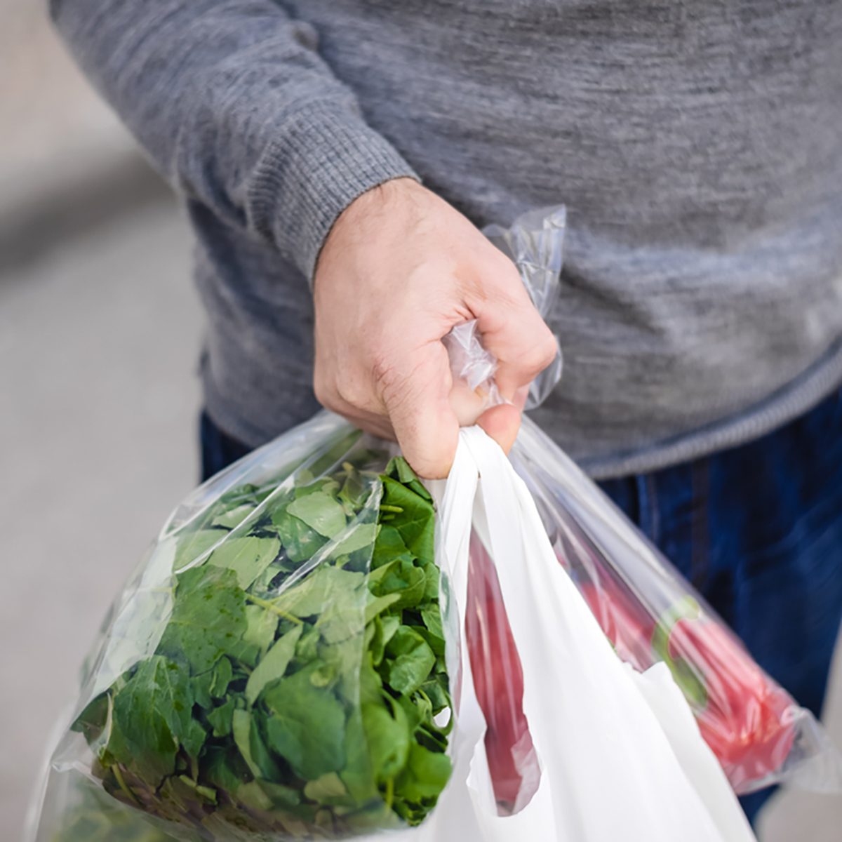 Male carrying bag in his hand after shopping. Closeup of bag full of fruits and vegetables.