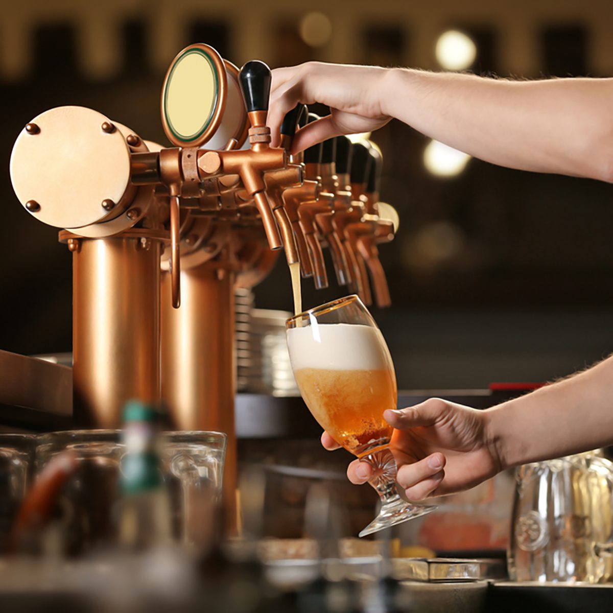Barman hands pouring a lager beer in a glass.