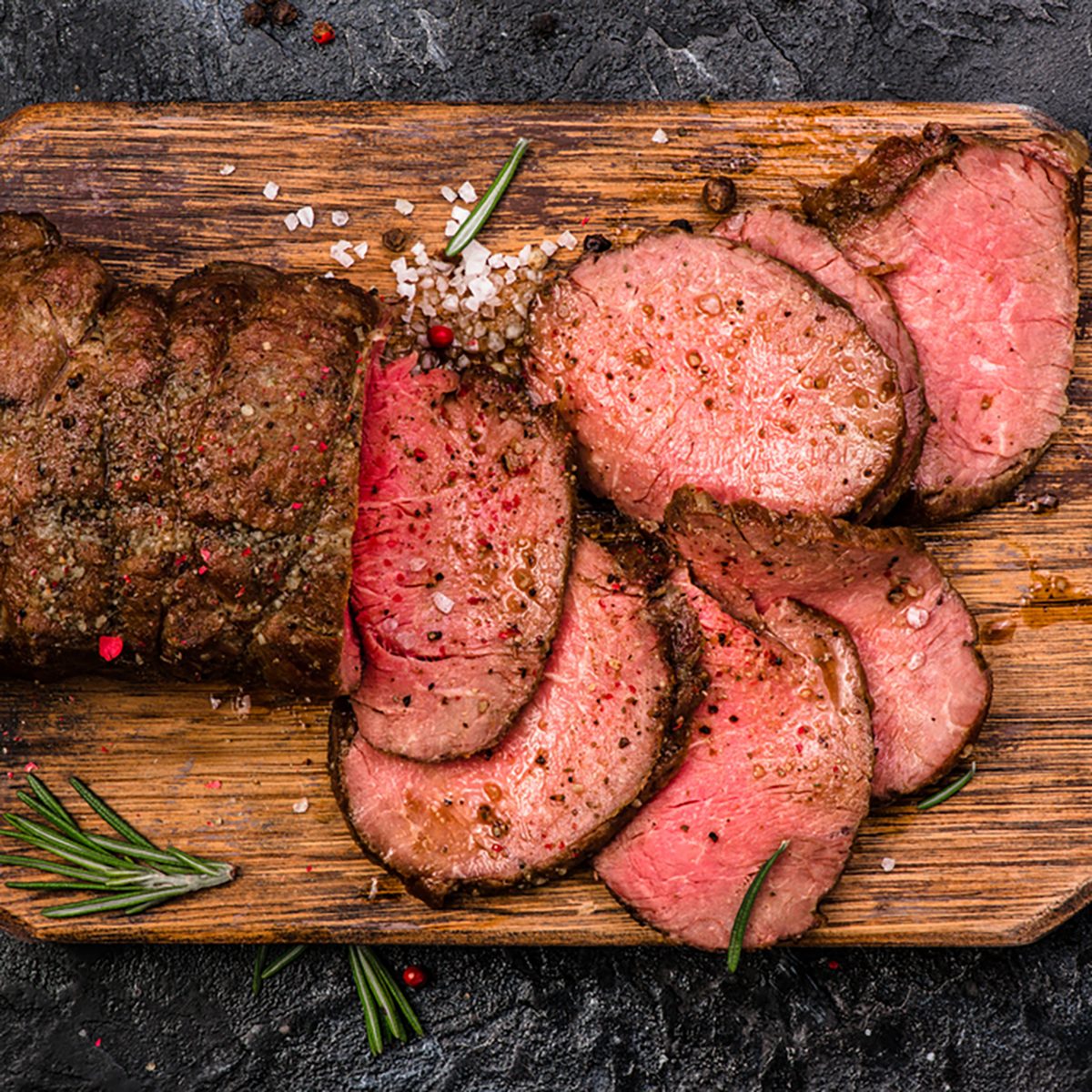 Roast beef on cutting board with salt and pepper. 