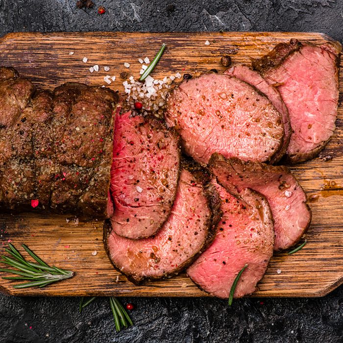 Roast beef on cutting board with salt and pepper.
