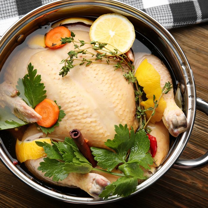 Cooking pot with turkey soaked in flavored brine on wooden table