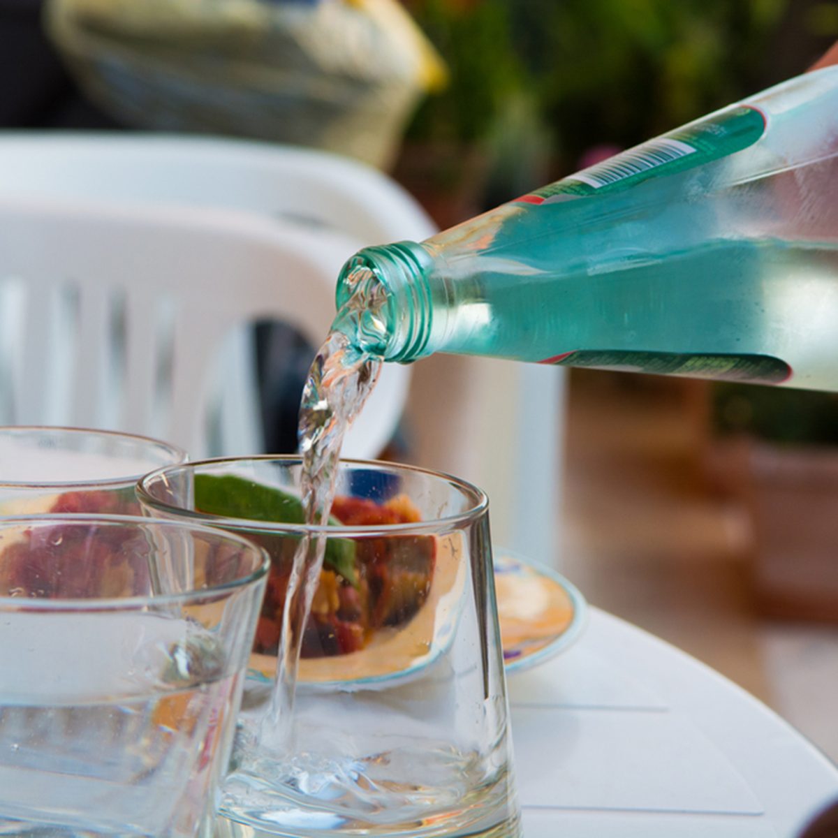 Waiter pouring mineral water from the glass bottle into a glass