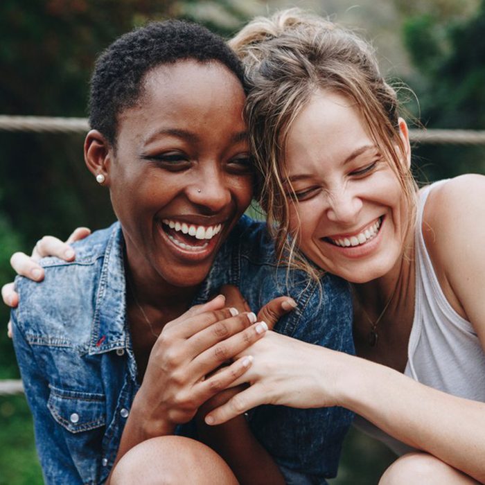 Two women laughing and side-hugging each other