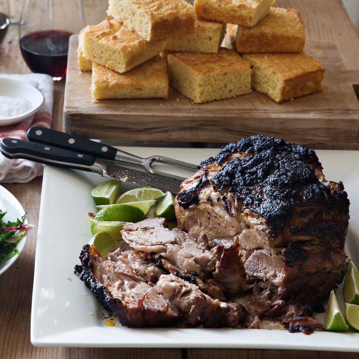Dinner spread of a large piece of meat, salad, and stack of cornbread