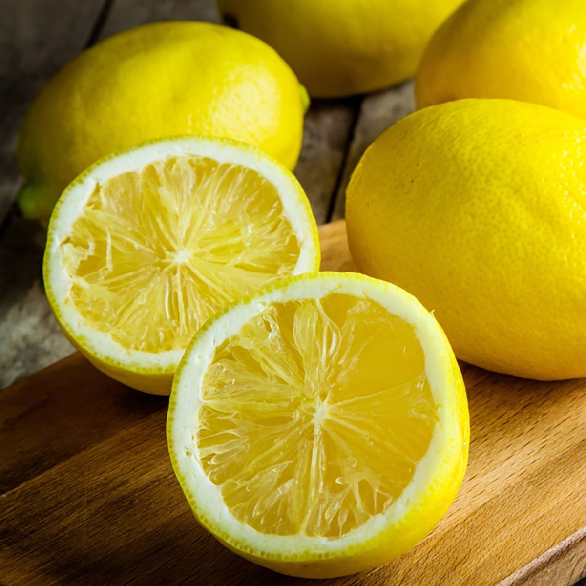 Fresh juicy lemons on a cutting board on a rustic wooden 
