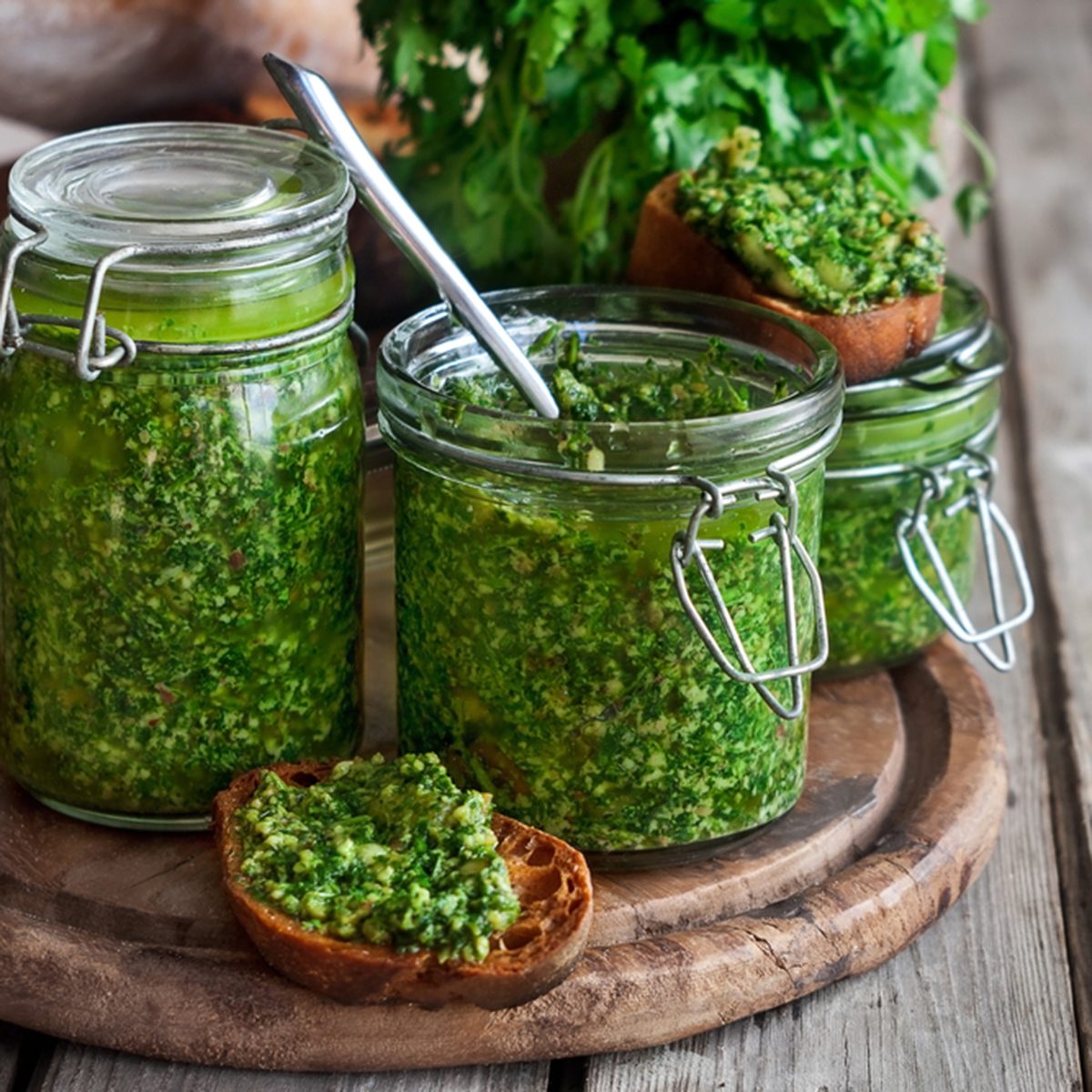 Homemade cilantro pesto in jars on wooden background