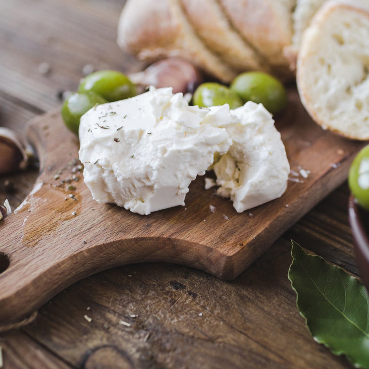Green olives, sliced ciabatta, feta cheese on a wooden board