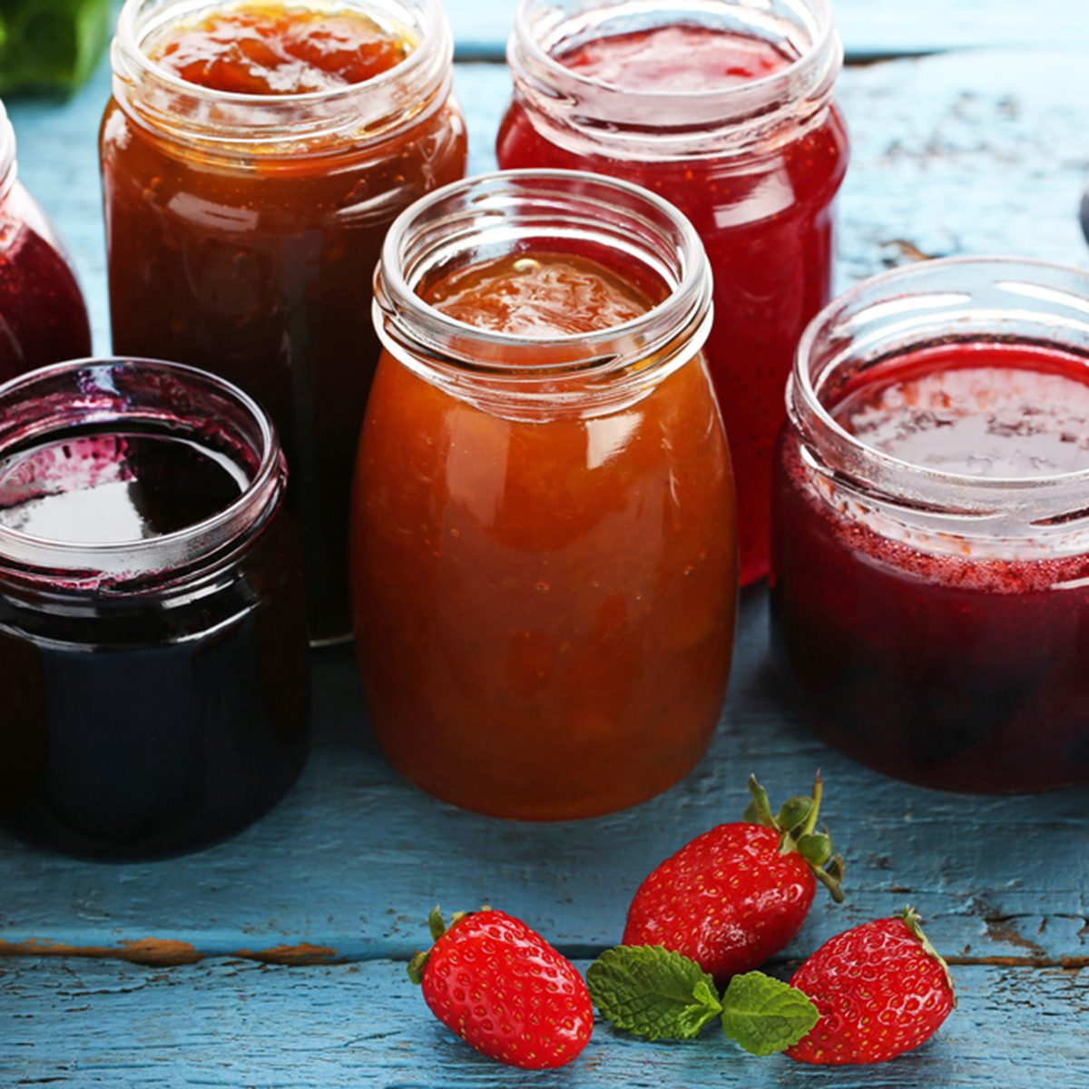 Glass jars with different kinds of jam and berries on wooden table