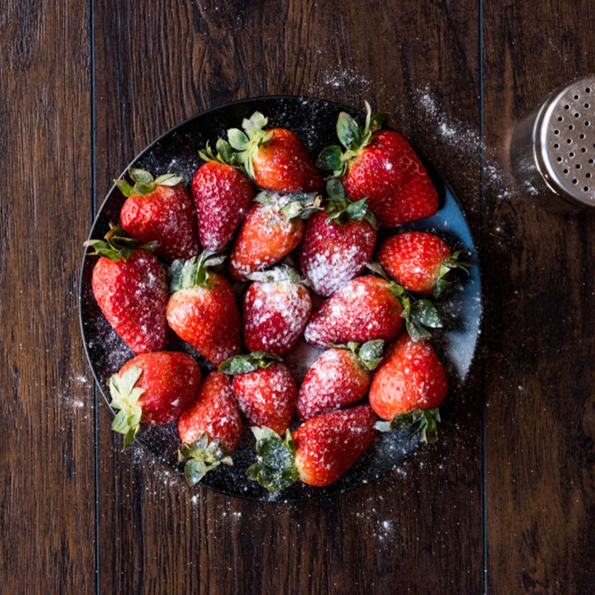 Fresh Organic Ripe Strawberries with Powdered Sugar on Black Plate.