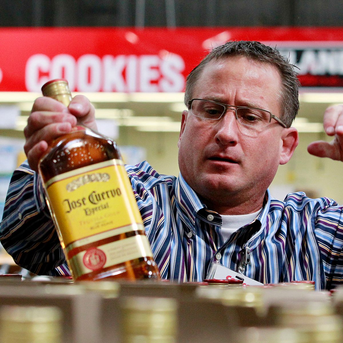 Store manager Todd Young smiles as he restocks tequila at a Costco warehouse store