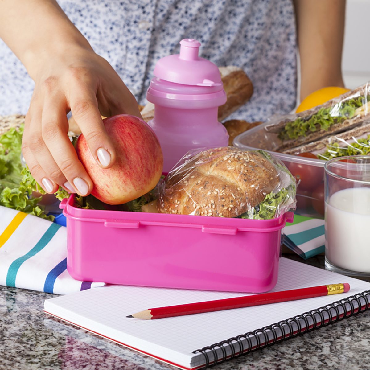Woman preparing lunchboxes with fruits and sandwiches for school