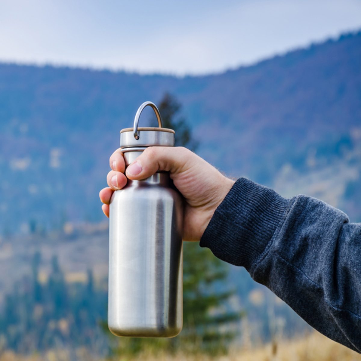 Man holding a bottle on the carpathian mountains background