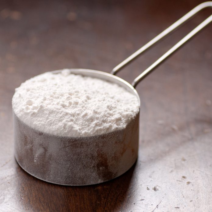 metal measure cup of white flour for baking