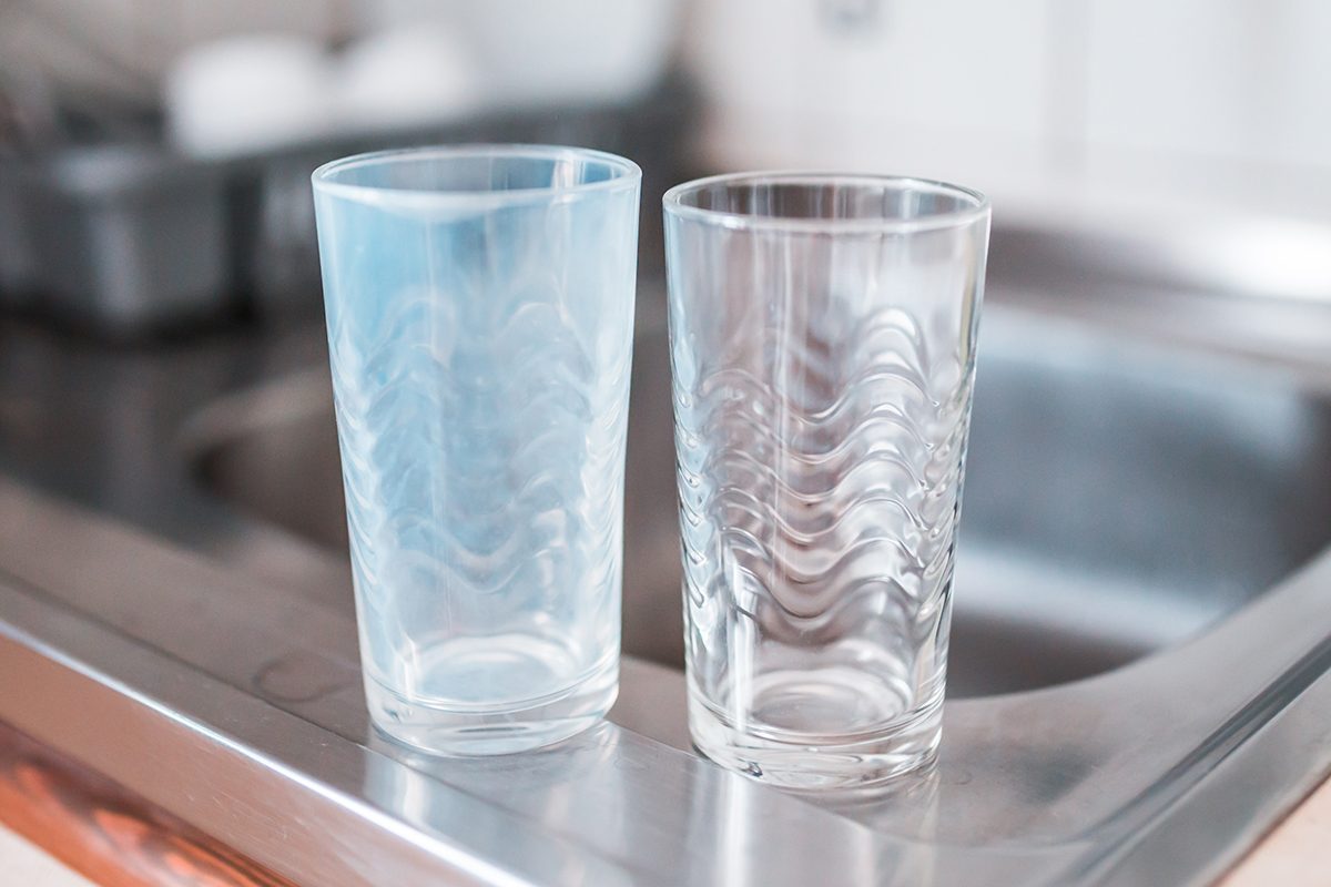 Dirty And Clean Glass Cups On A Kitchen Sink. Broken Washing Machine Concept.