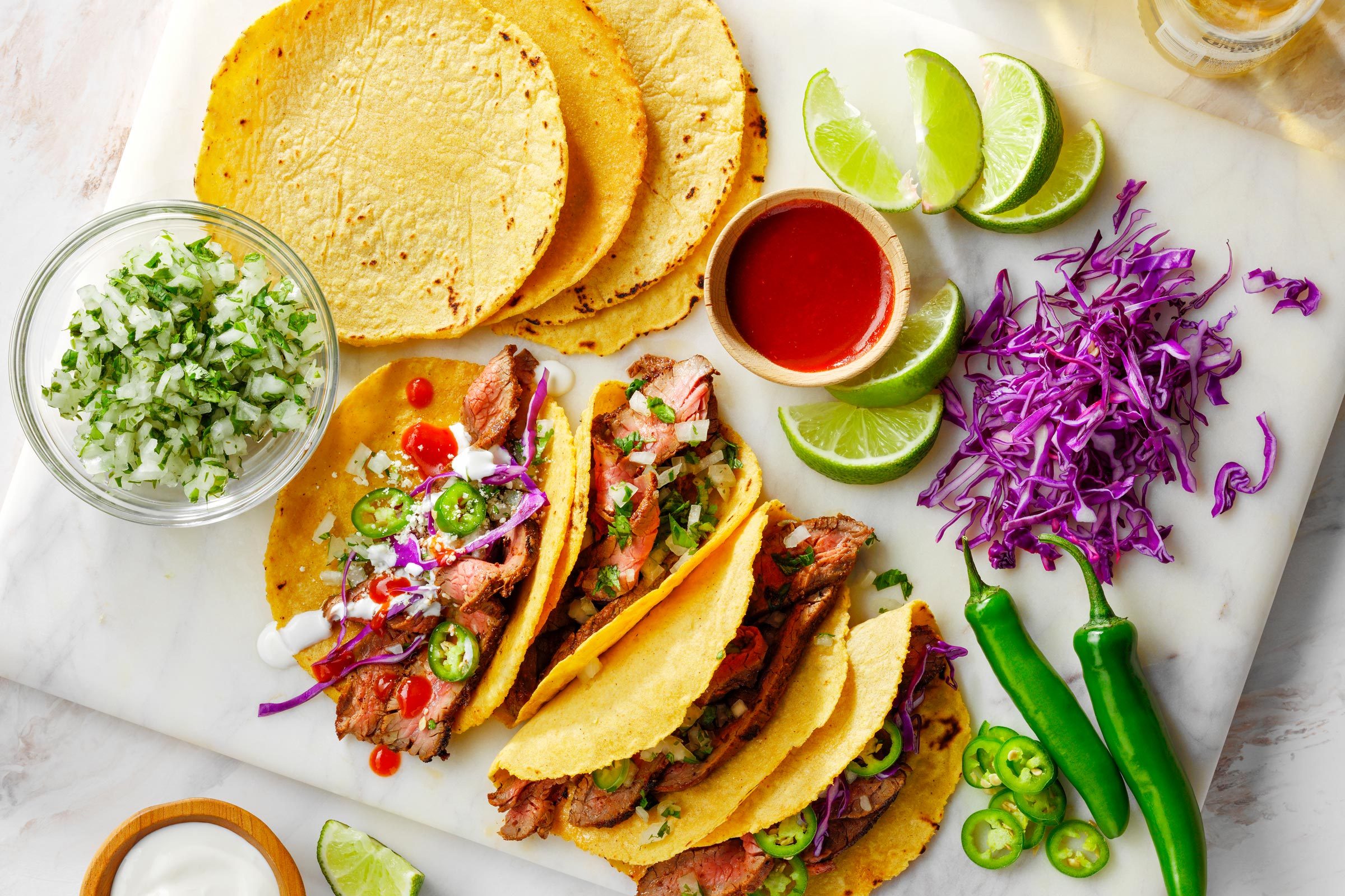 Corn tortillas and tacos laid out on a marble board