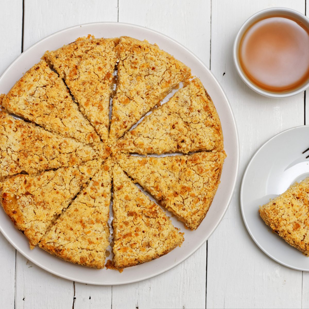 Homemade pie with cheese and apples, cup of tea and fork on white wooden table