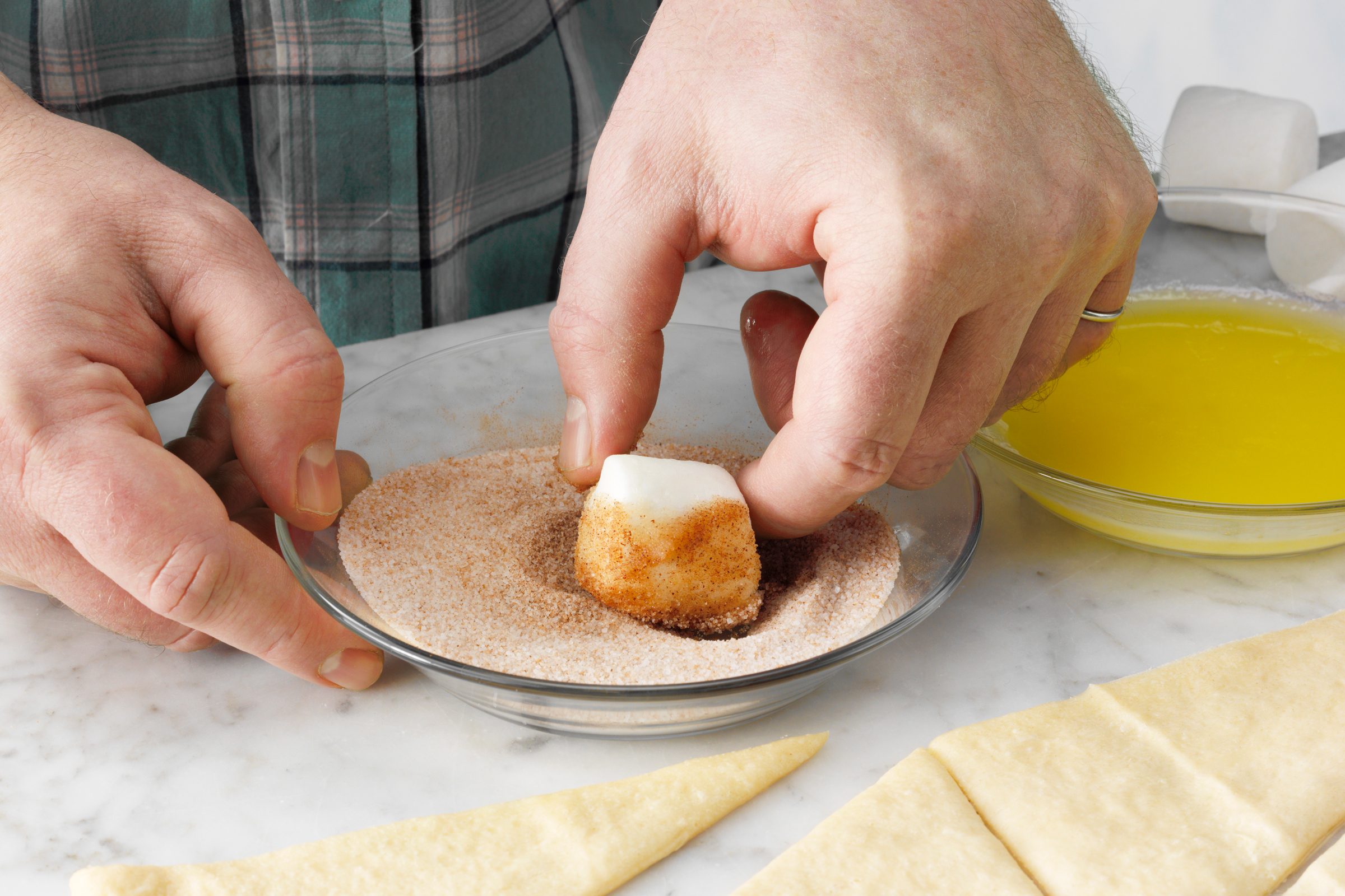dipping a marshmallow in cinnamon sugar
