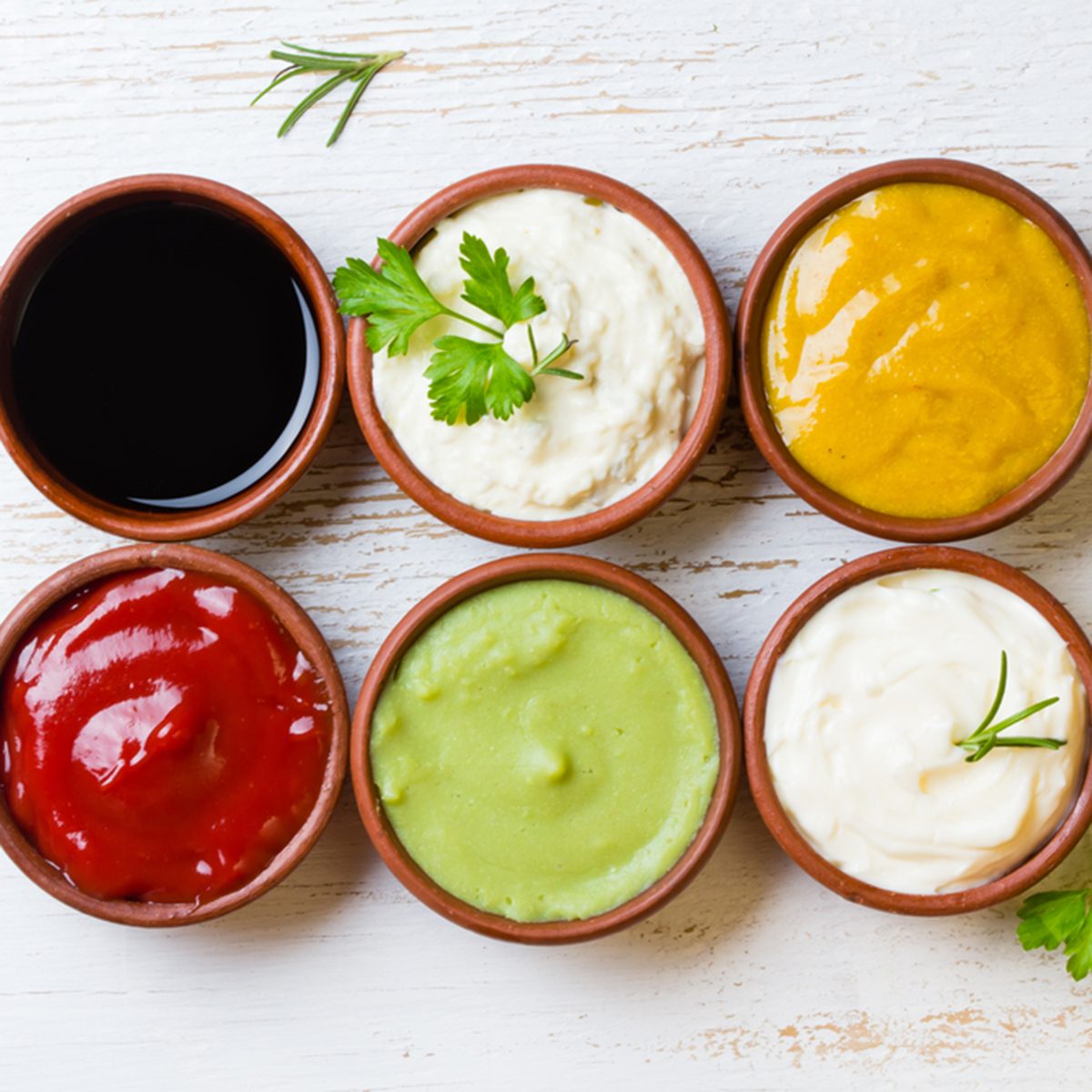 Sauces ketchup, mustard, mayonnaise, wasabi, soy sauce in clay bowls on wooden white background