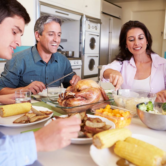 Family Sitting Around Table At Home Eating Meal