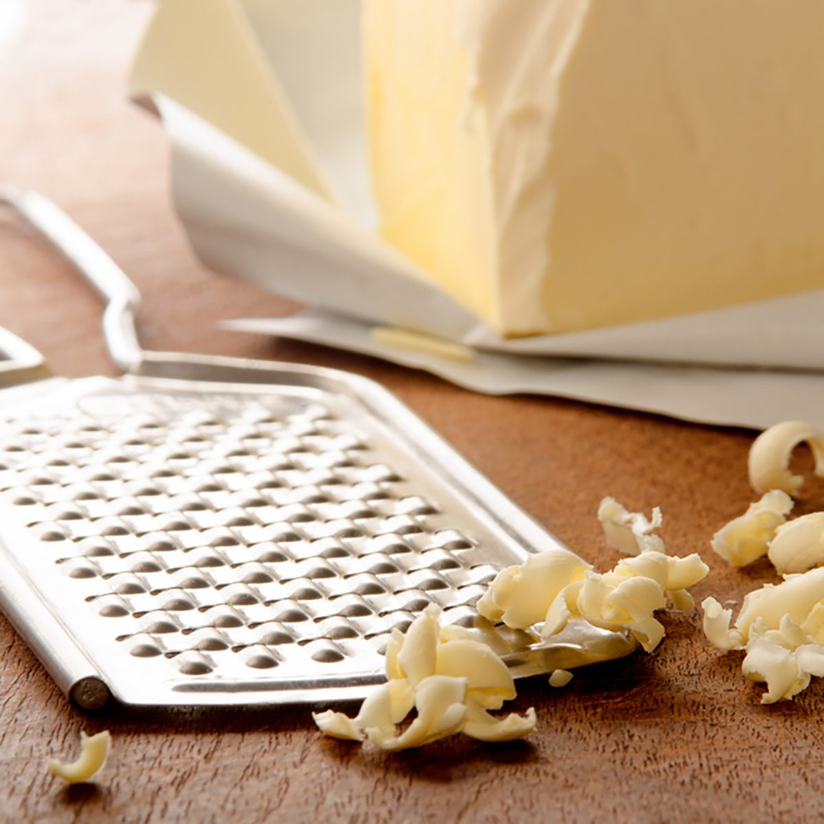 grated butter and grater on wooden board