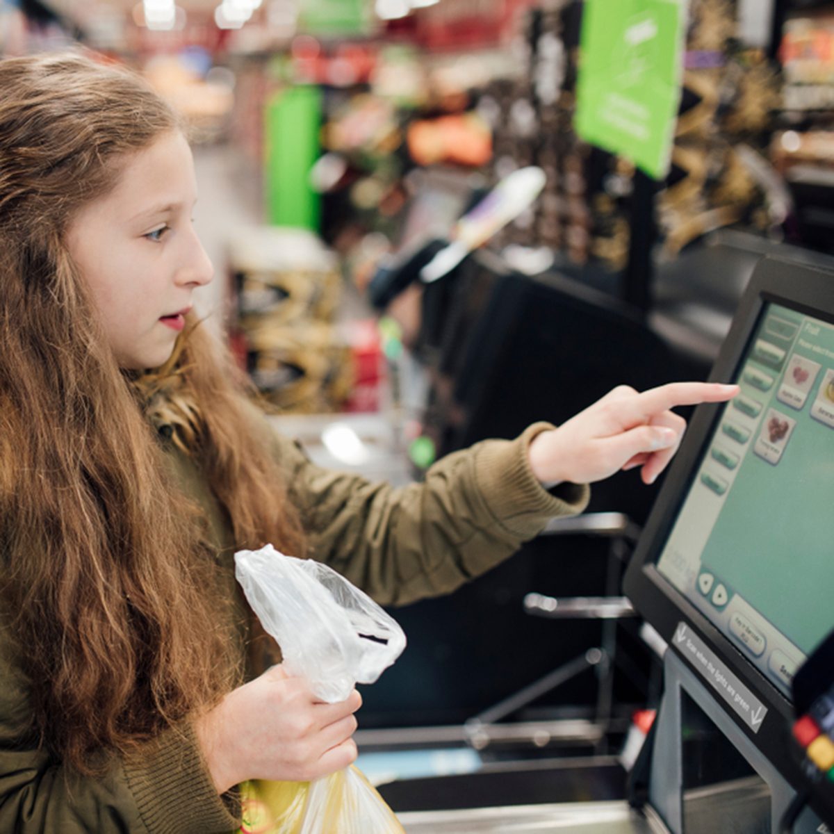 Little girl is at the self service checkout of the supermarket with her father.