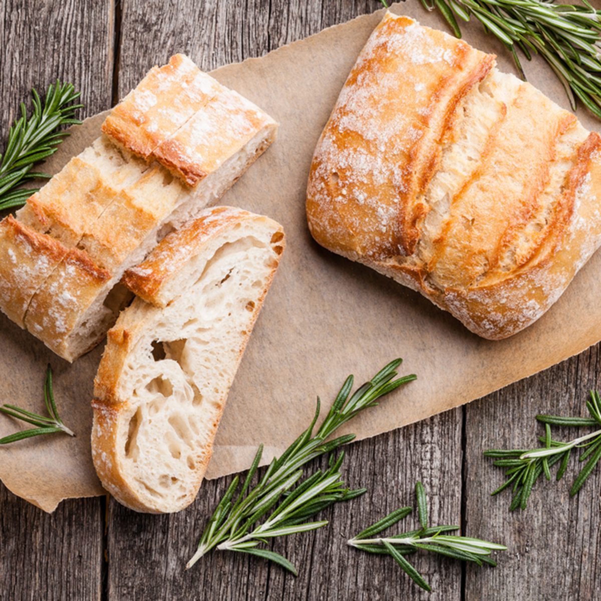 Sliced bread Ciabatta and rosemary on wooden background