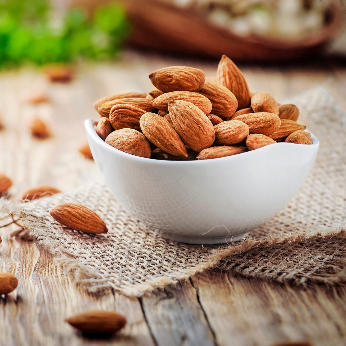 Almonds in white porcelain bowl on wooden table