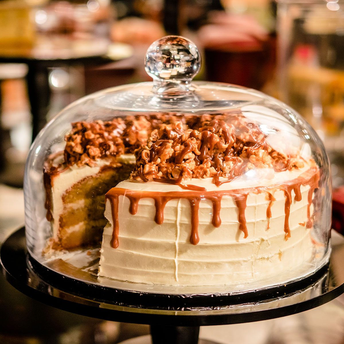 Caramel cake under glass bell dome.