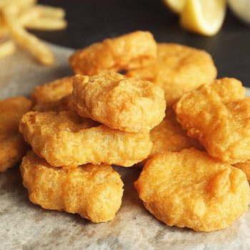 Tasty fried nuggets on paper, closeup
