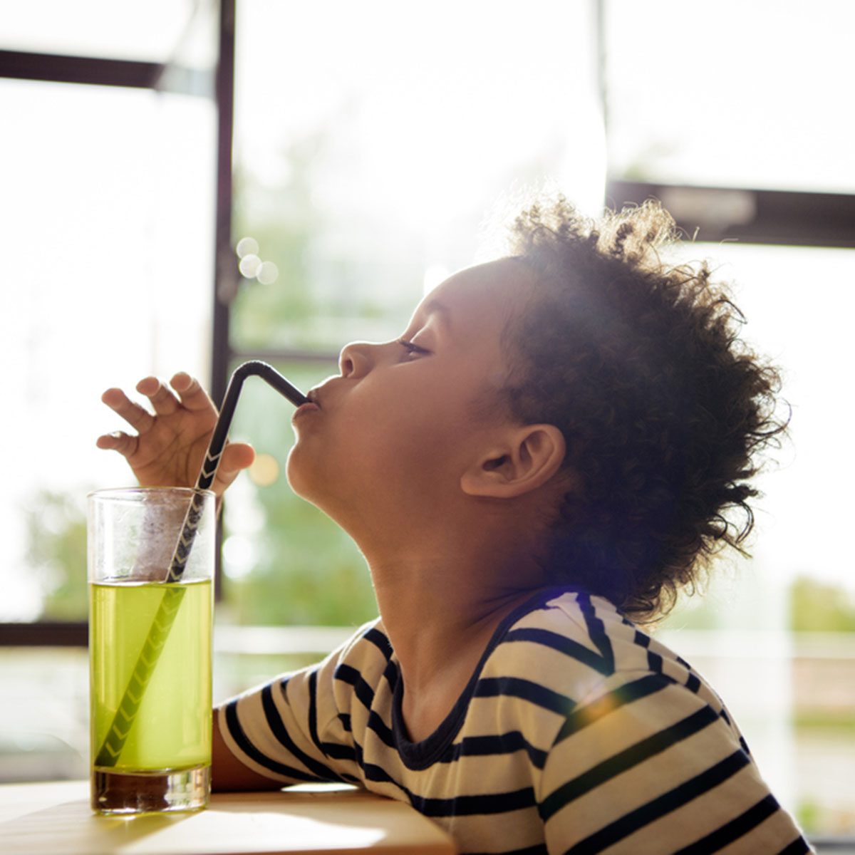 Side view of beautiful african american boy drinking lemonade in cafe