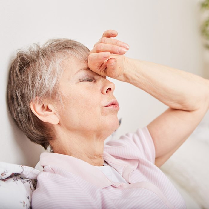 Ill senior woman with headache