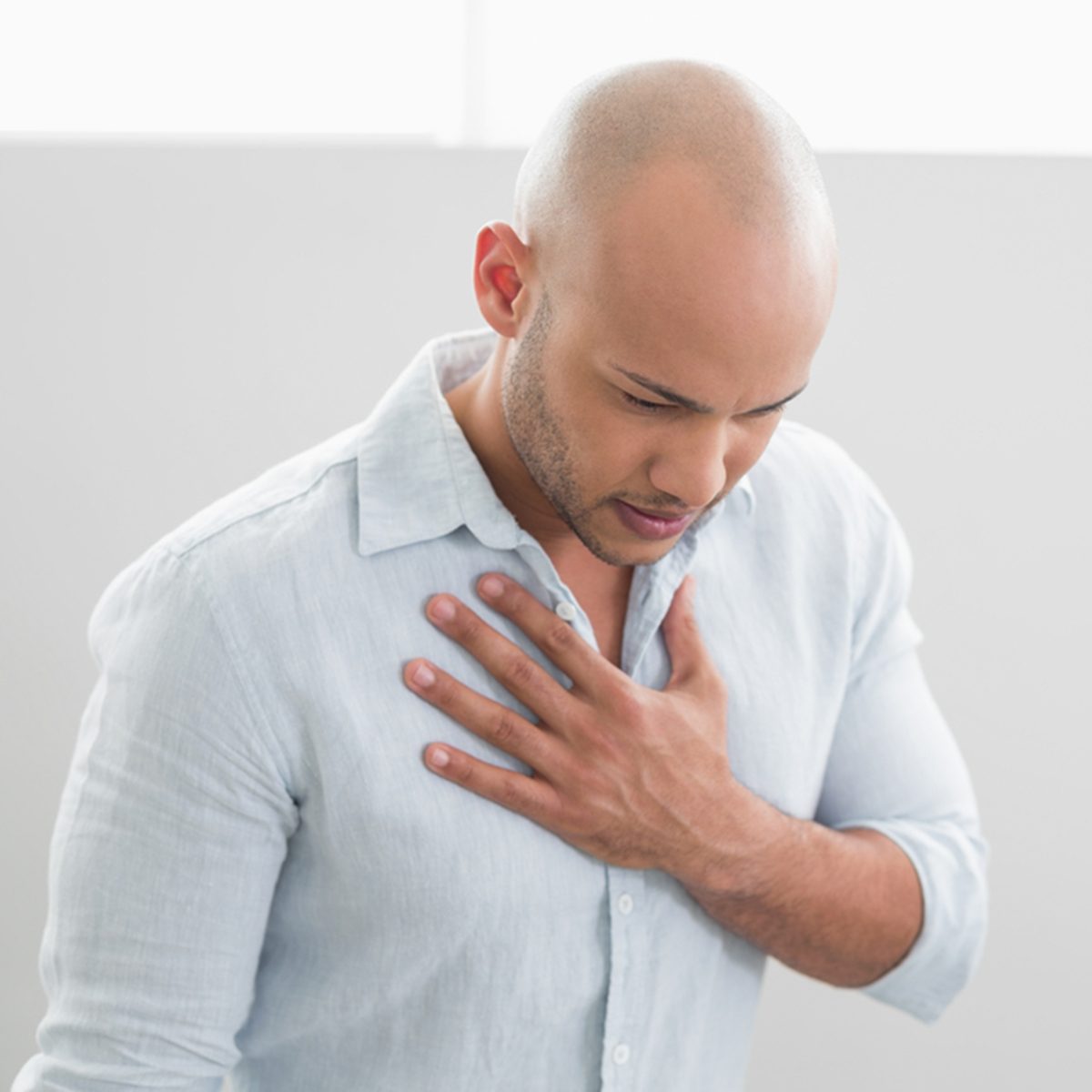 Casual young man with chest pain standing against white background