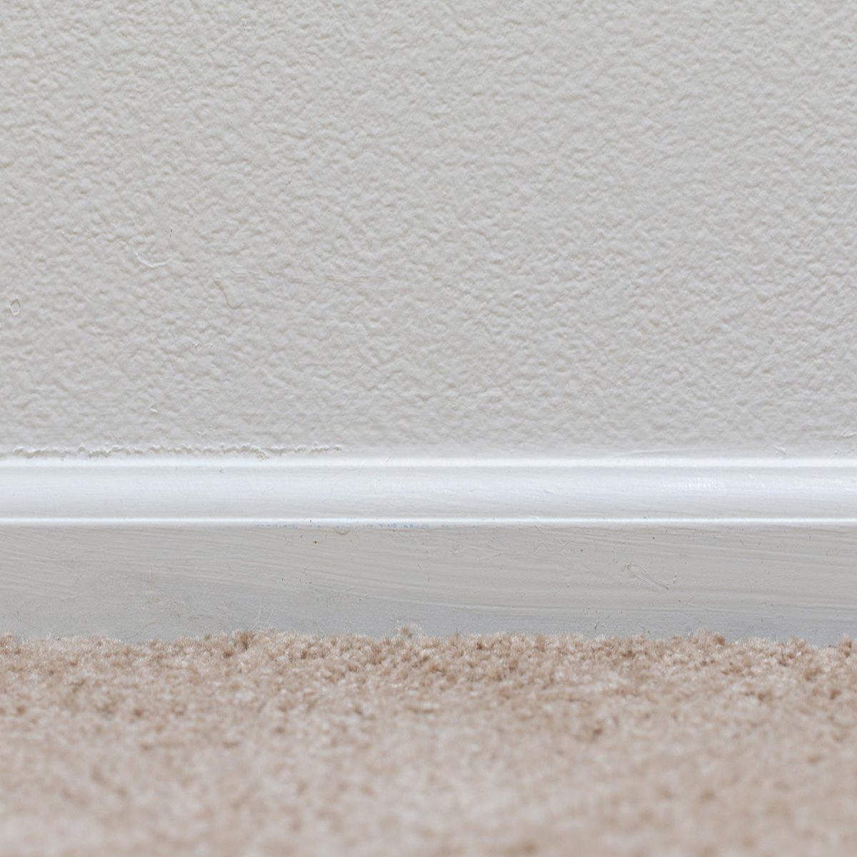 Basic floor trim up against a tan carpeted floor