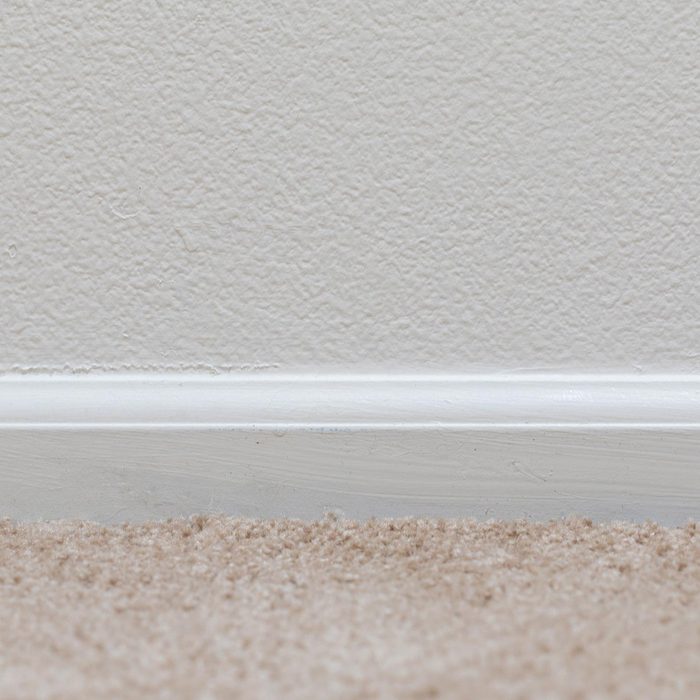 Basic floor trim up against a tan carpeted floor
