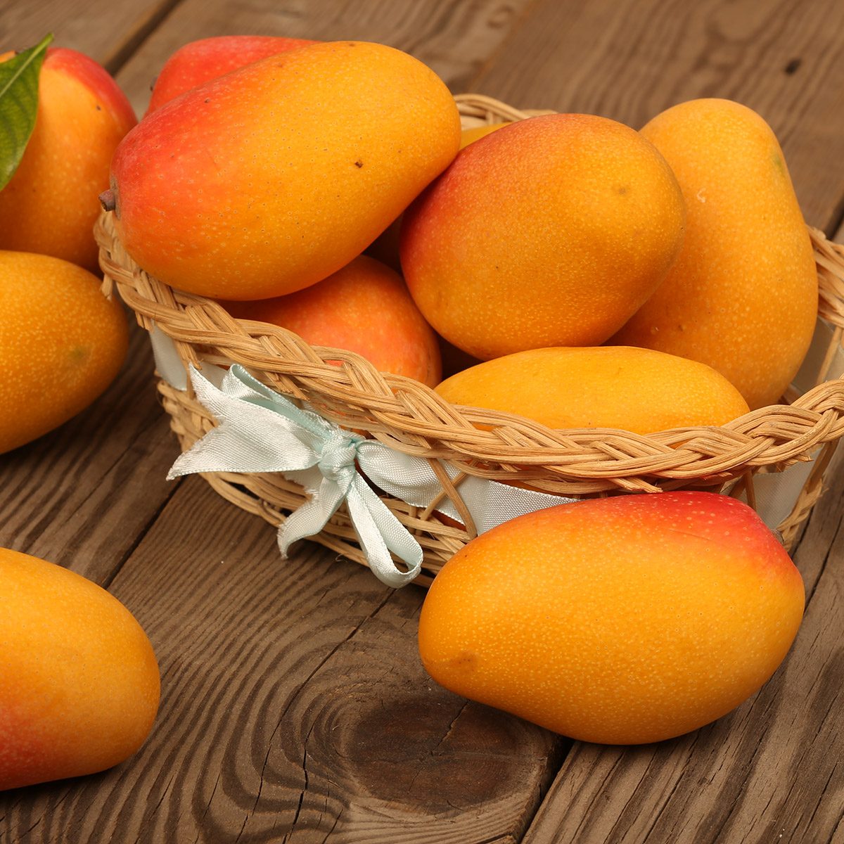 Ripe mango with mango leaf in wooden background.