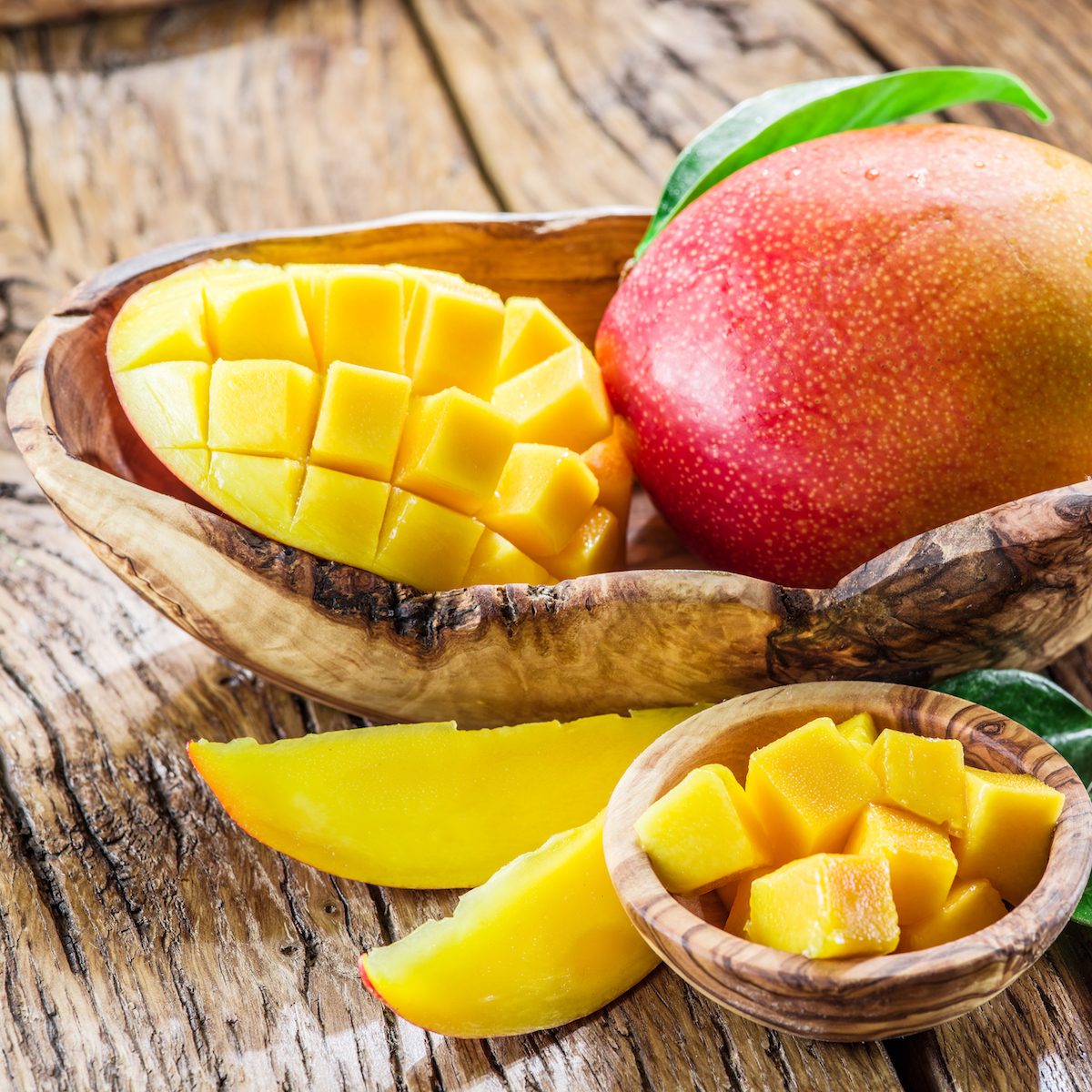 Mango fruit and mango cubes on the wooden table